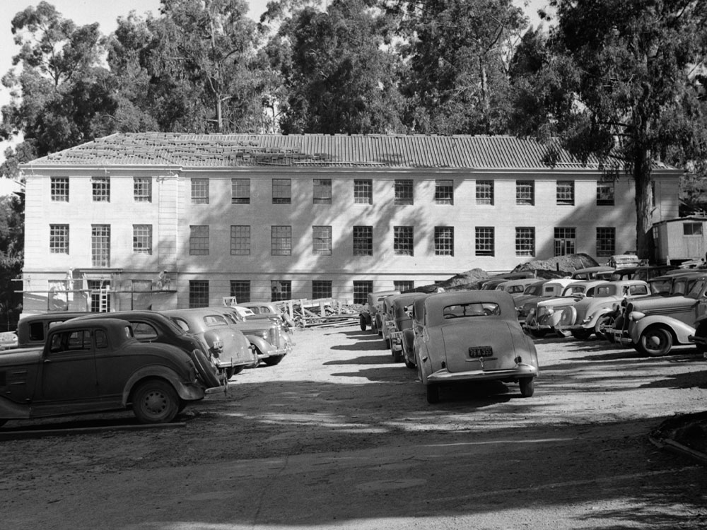 A black and white photo of the Donner Laboratory at the University of California, Berkeley. The parking lot is full of 1940s cars.